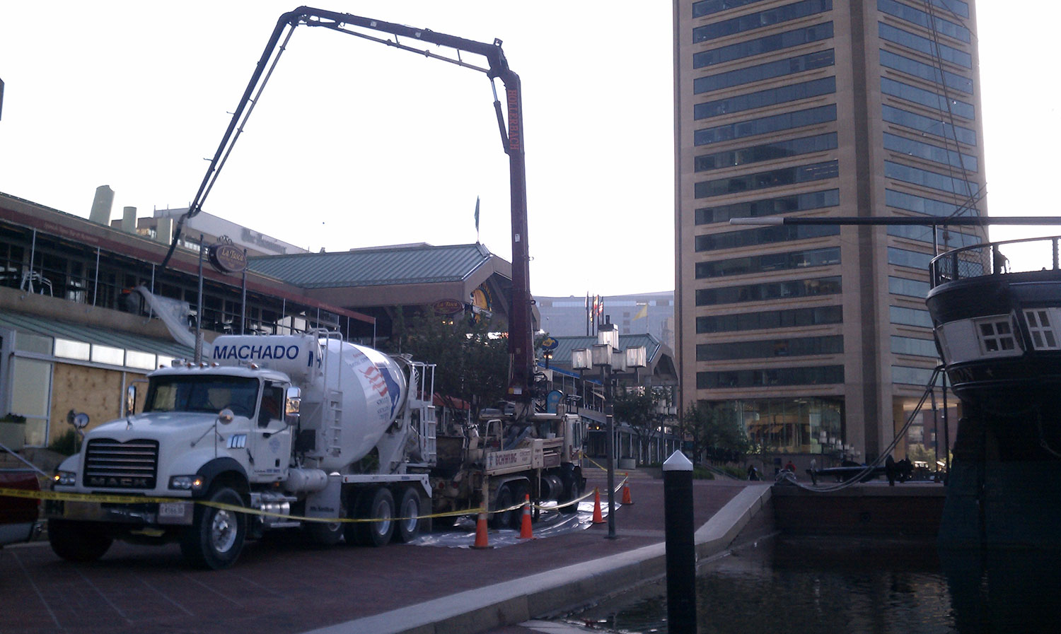boom pump pouring concrete on the second floor of a building from the street