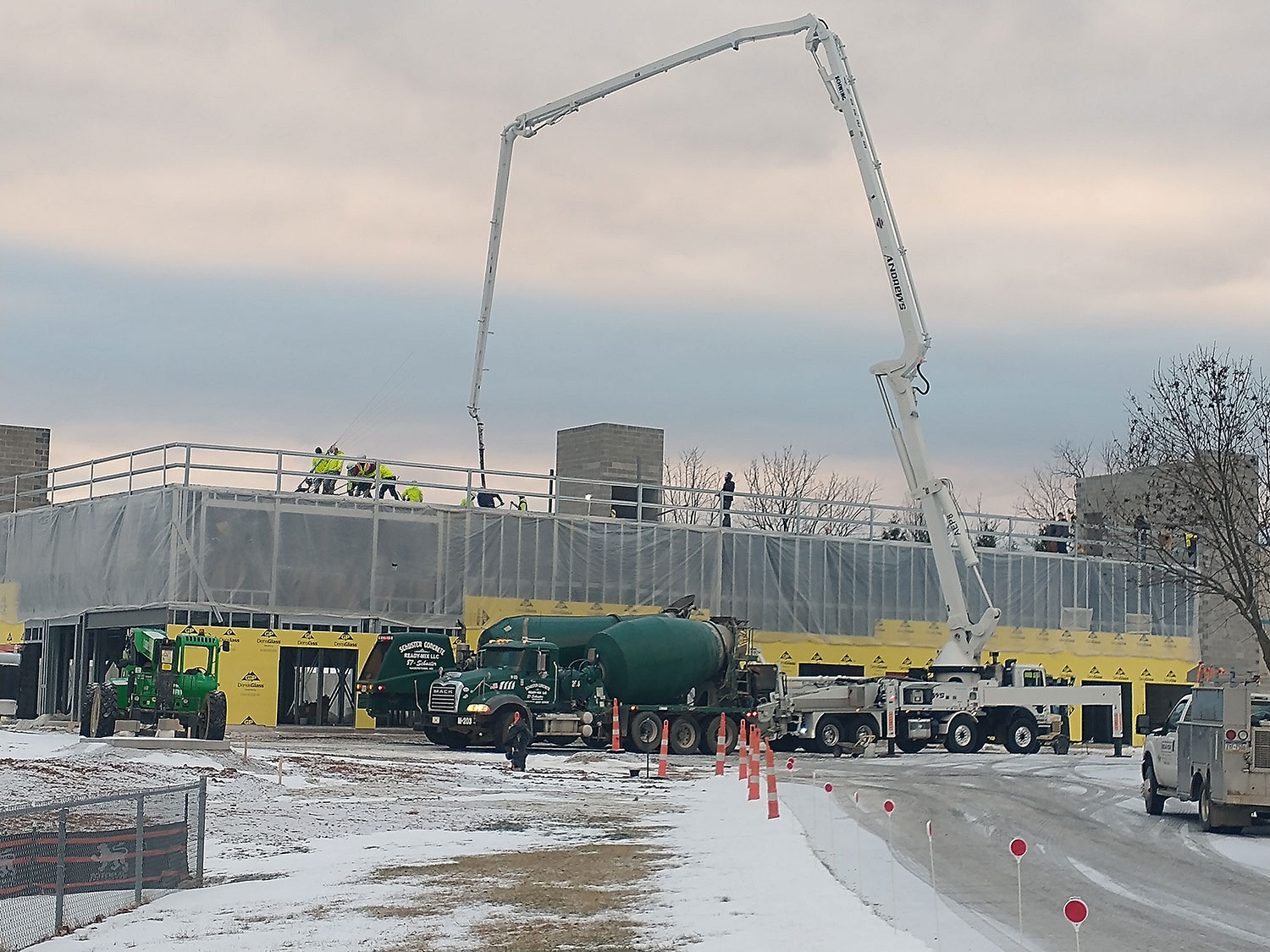 boom pump pouring concrete on the rooftop of a commercial building